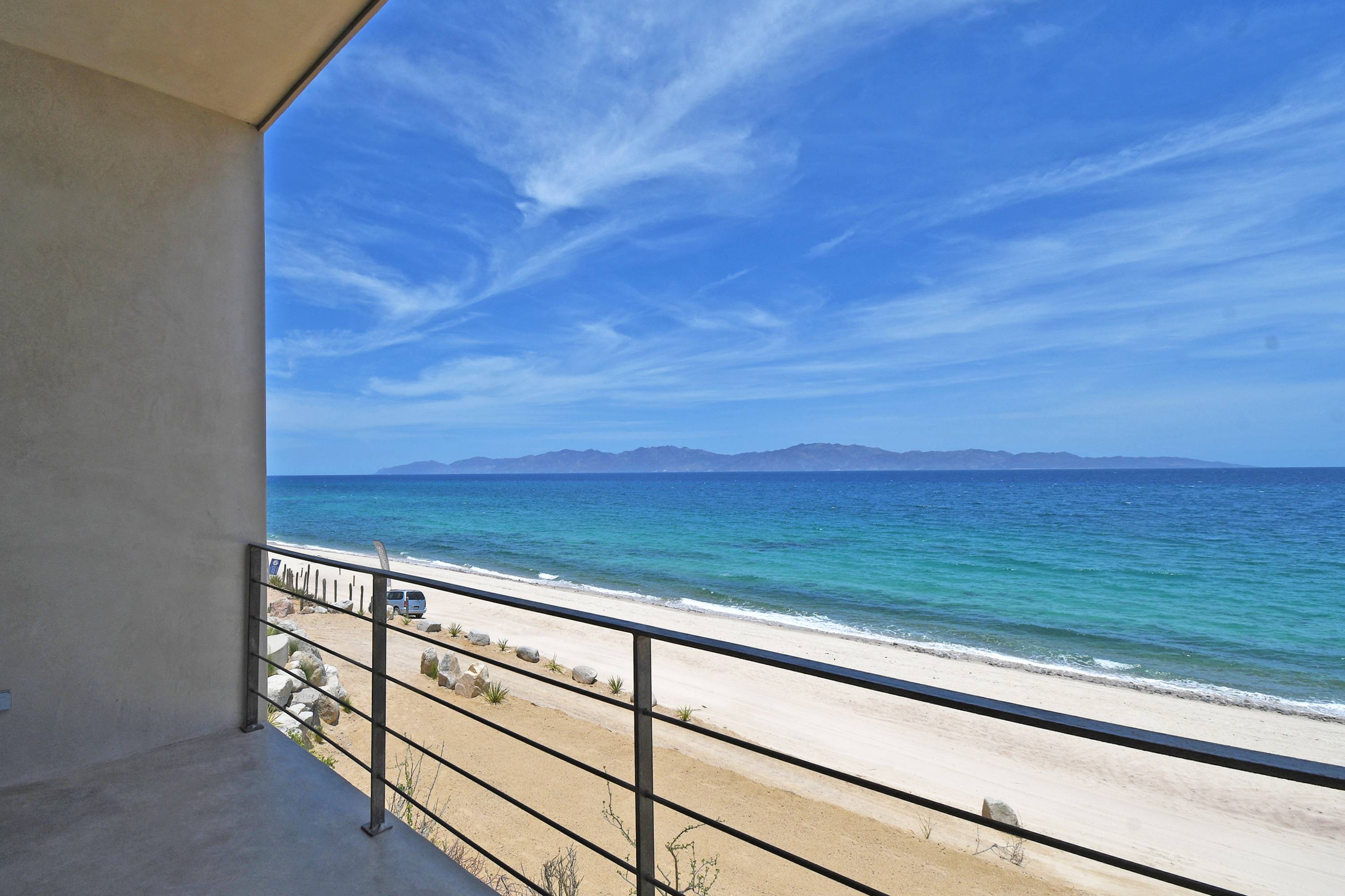 The view from a bedroom balcony along the beach, mountains across the bay.