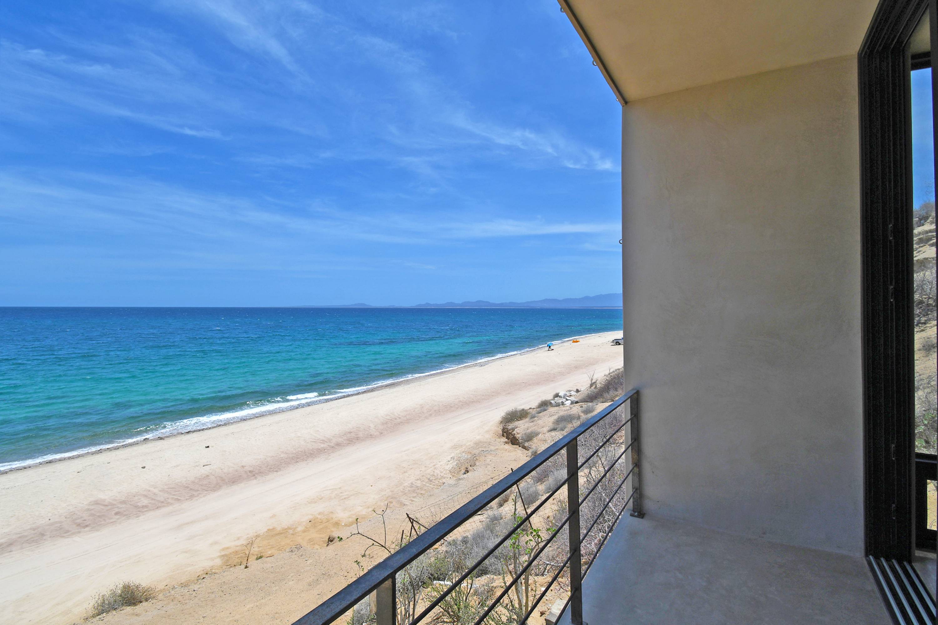 Looking down the beach from a bedroom balcony, the glass wall at the right.