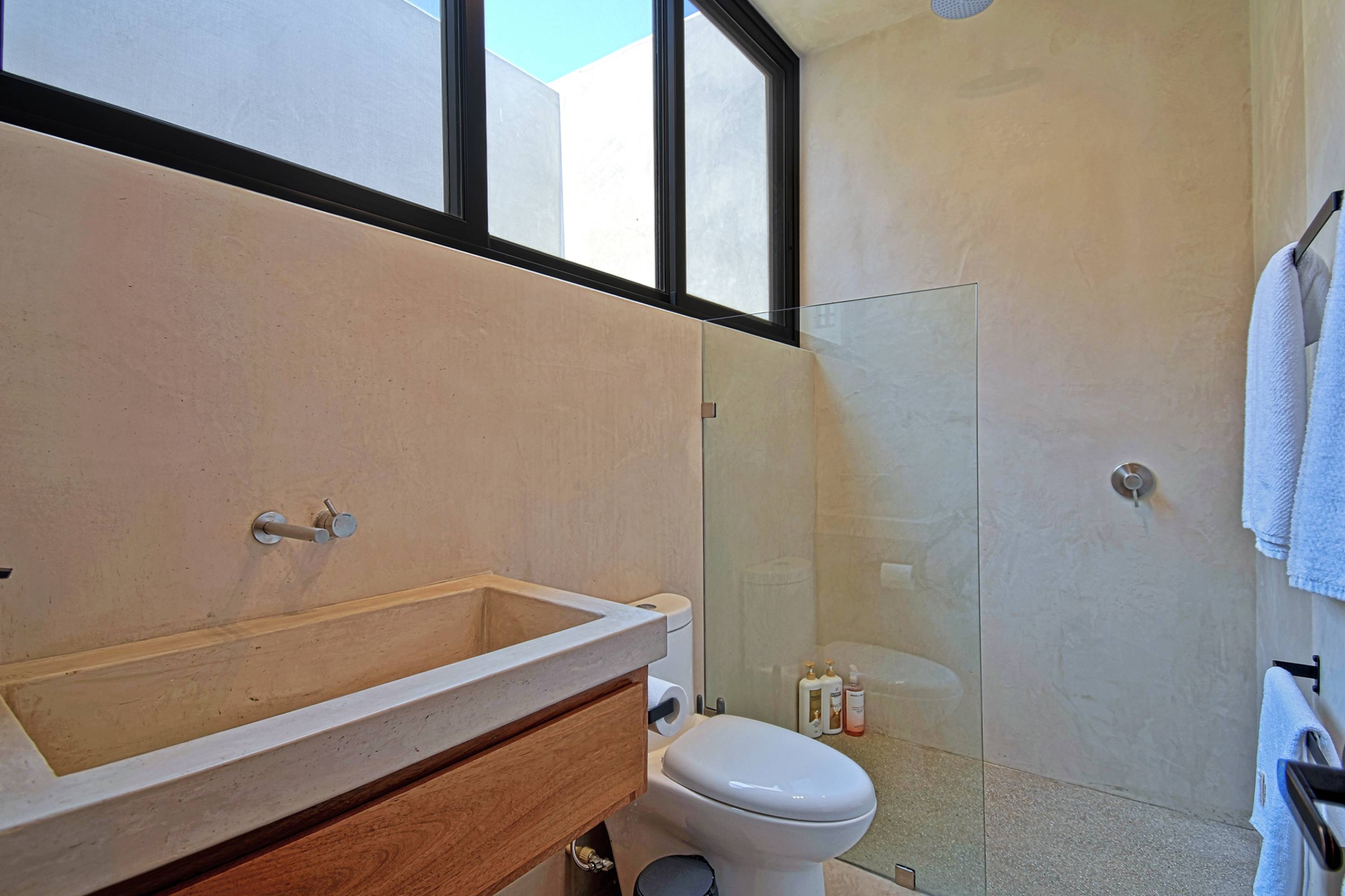The second bedroom's bathroom, concrete trough sink and a walk-in shower.