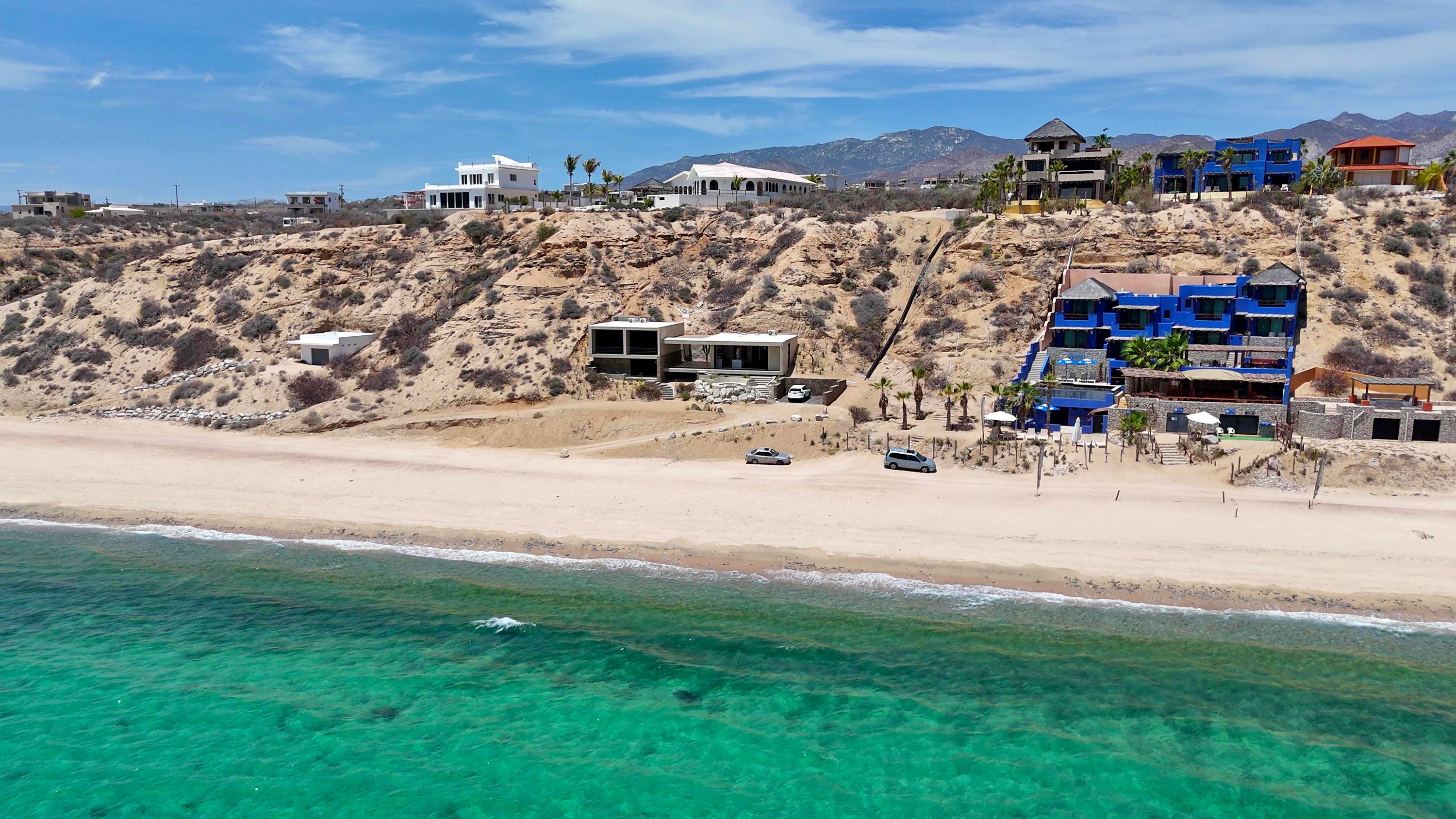 The house and its neighbours on the bluff above the beach, from the air.