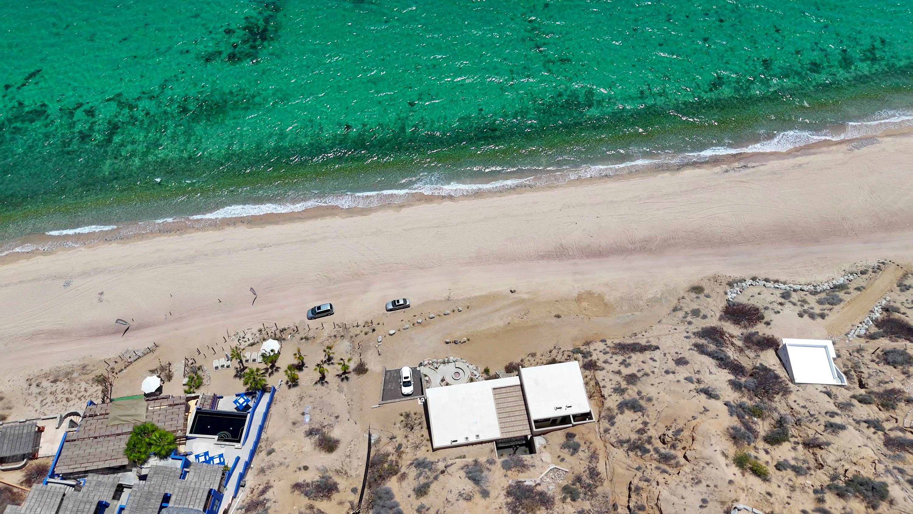 Overhead view of the beach with the houses set back from the sand.