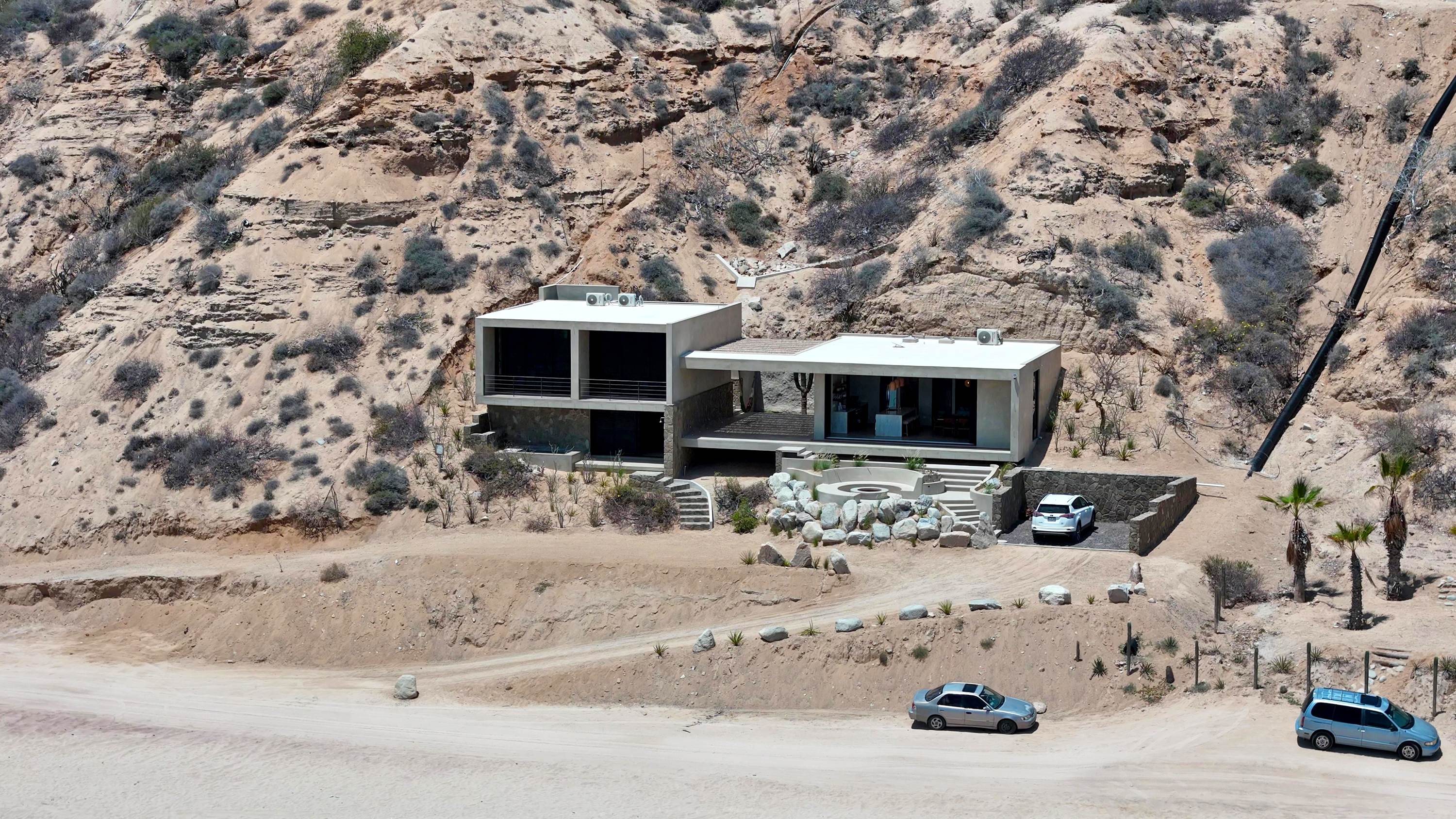 The driveway climbing from the beach track up to the house and its parking area.