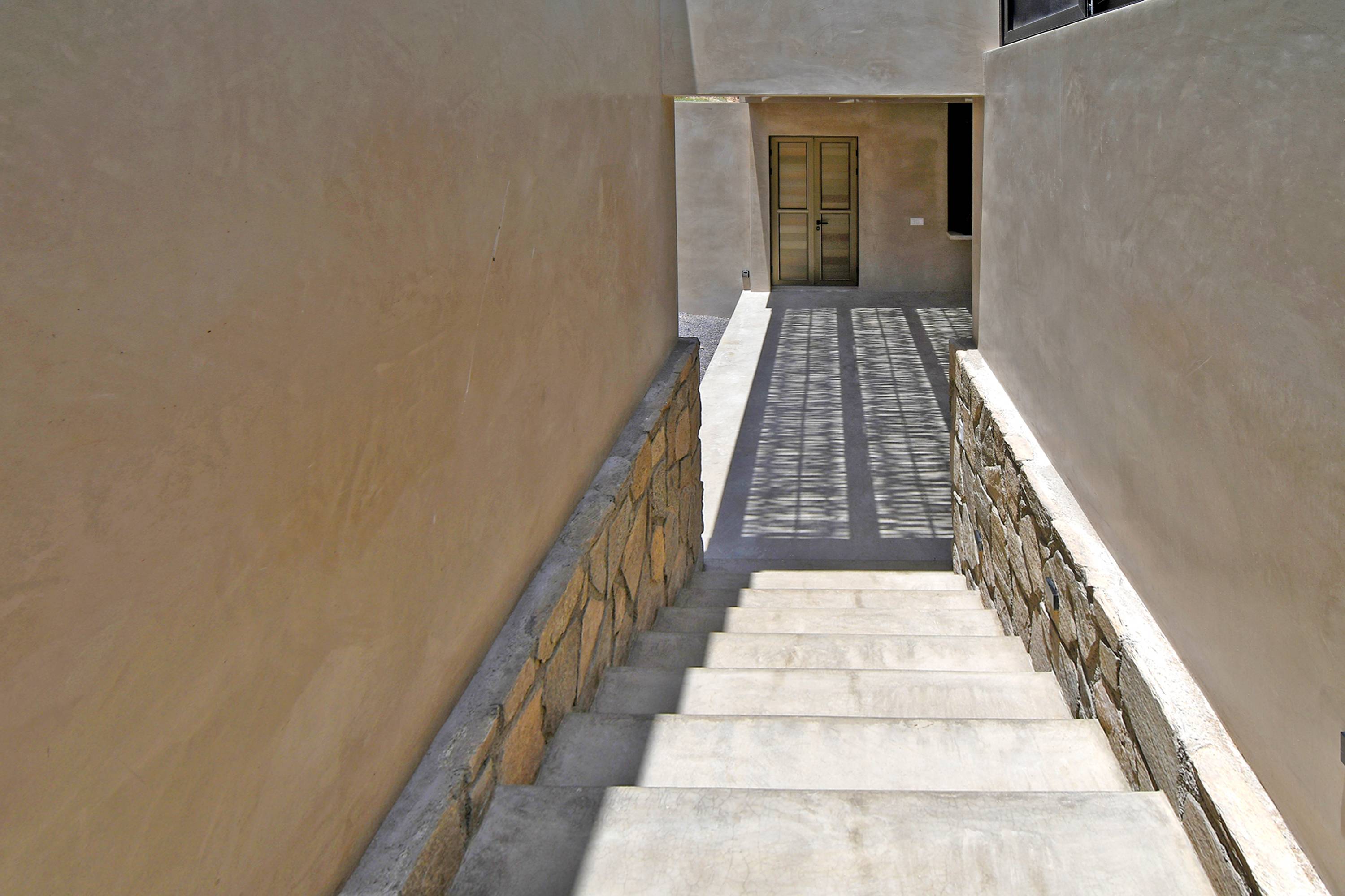 The stairs up to the bedrooms, plaster walls on a stone base with a door at the top.
