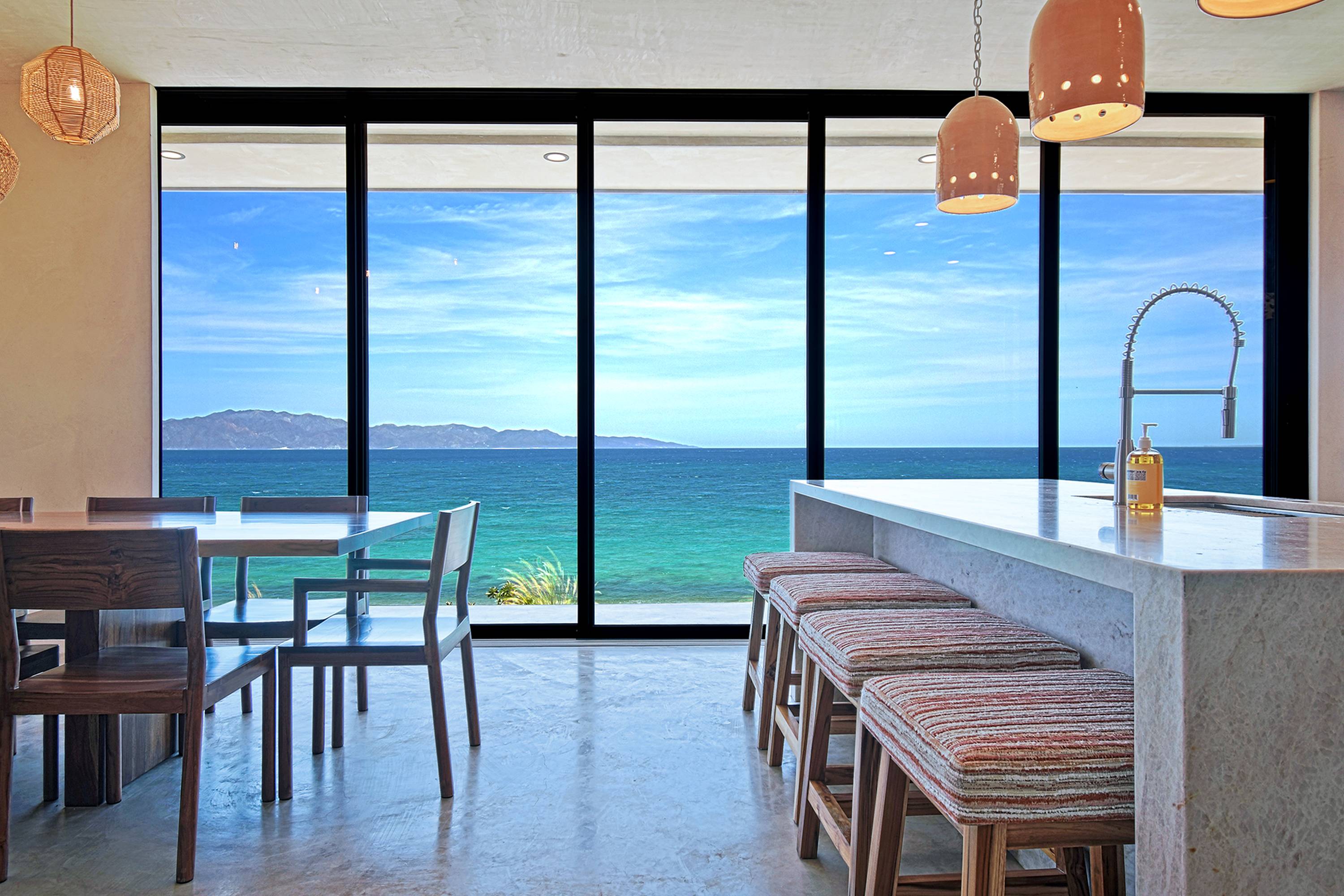 The kitchen island and bar stools, dining table and the glass front behind.