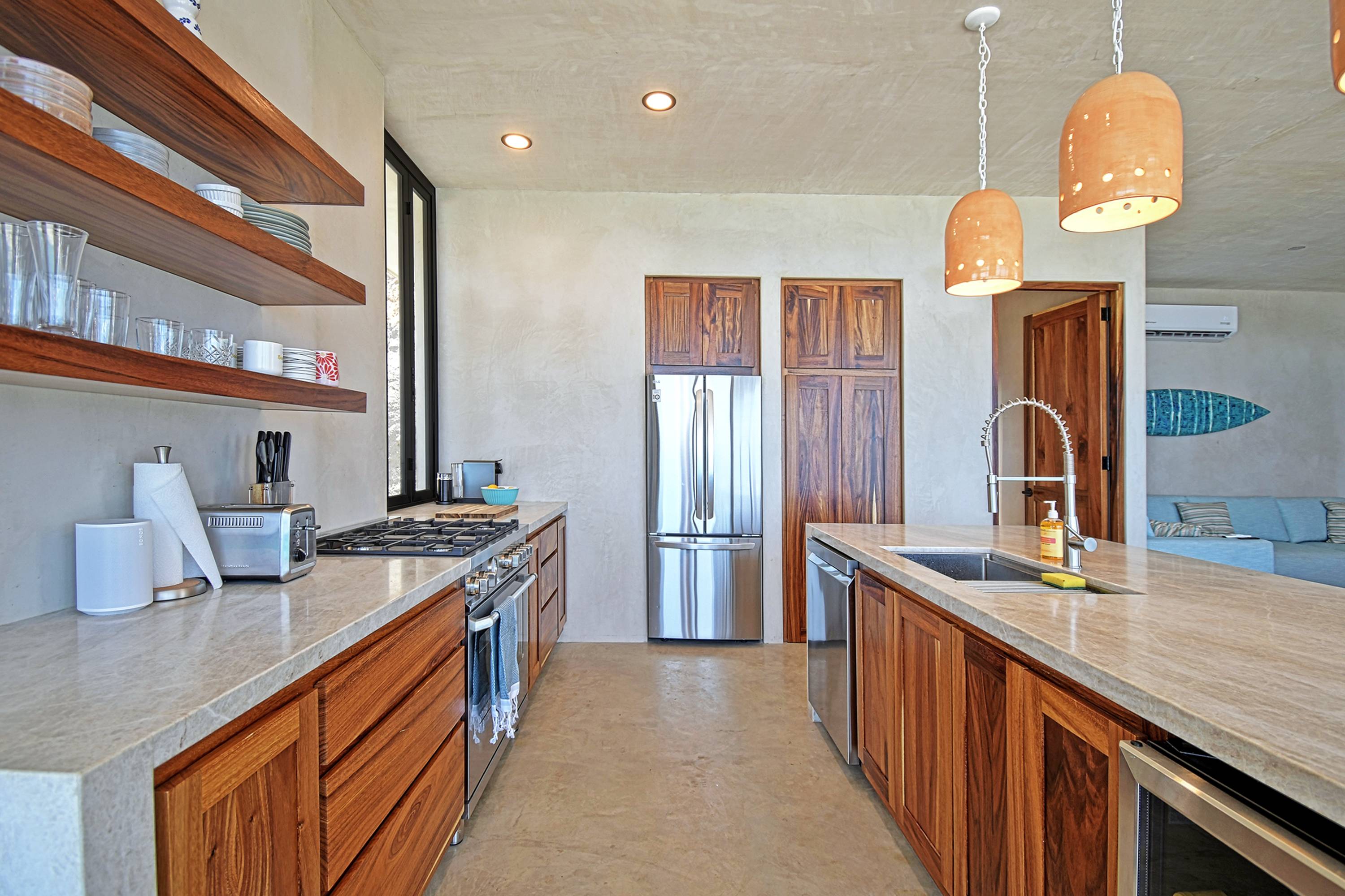 The kitchen run, range and open shelves, island in front.