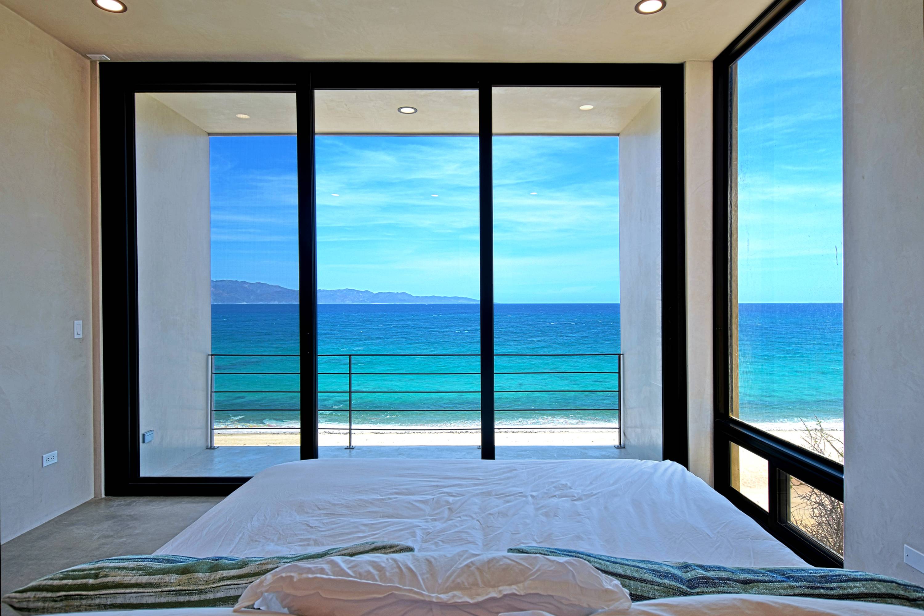 The master bed facing the glass wall and the water.