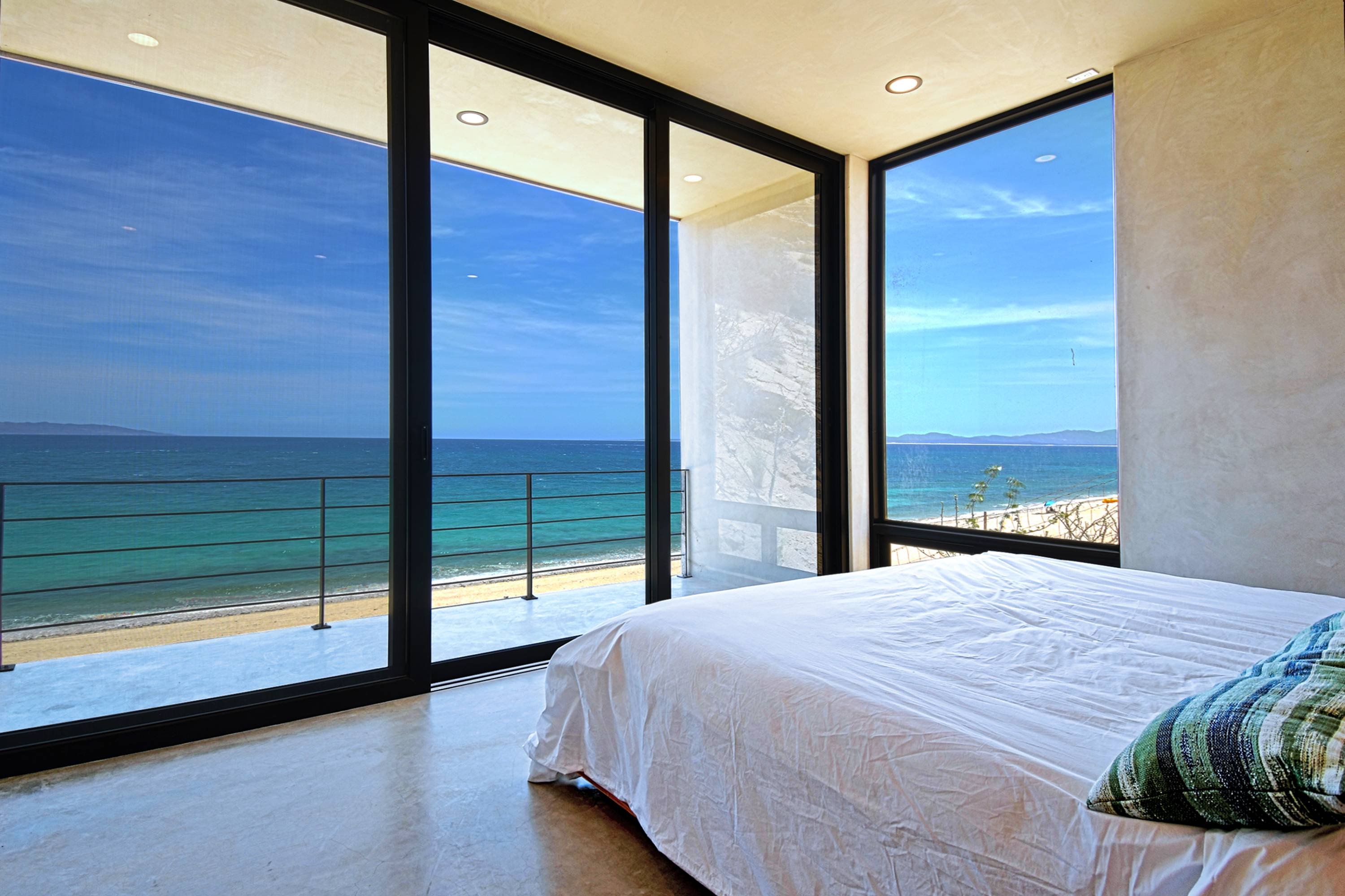 The master bedroom, glass on two sides and the balcony beyond.