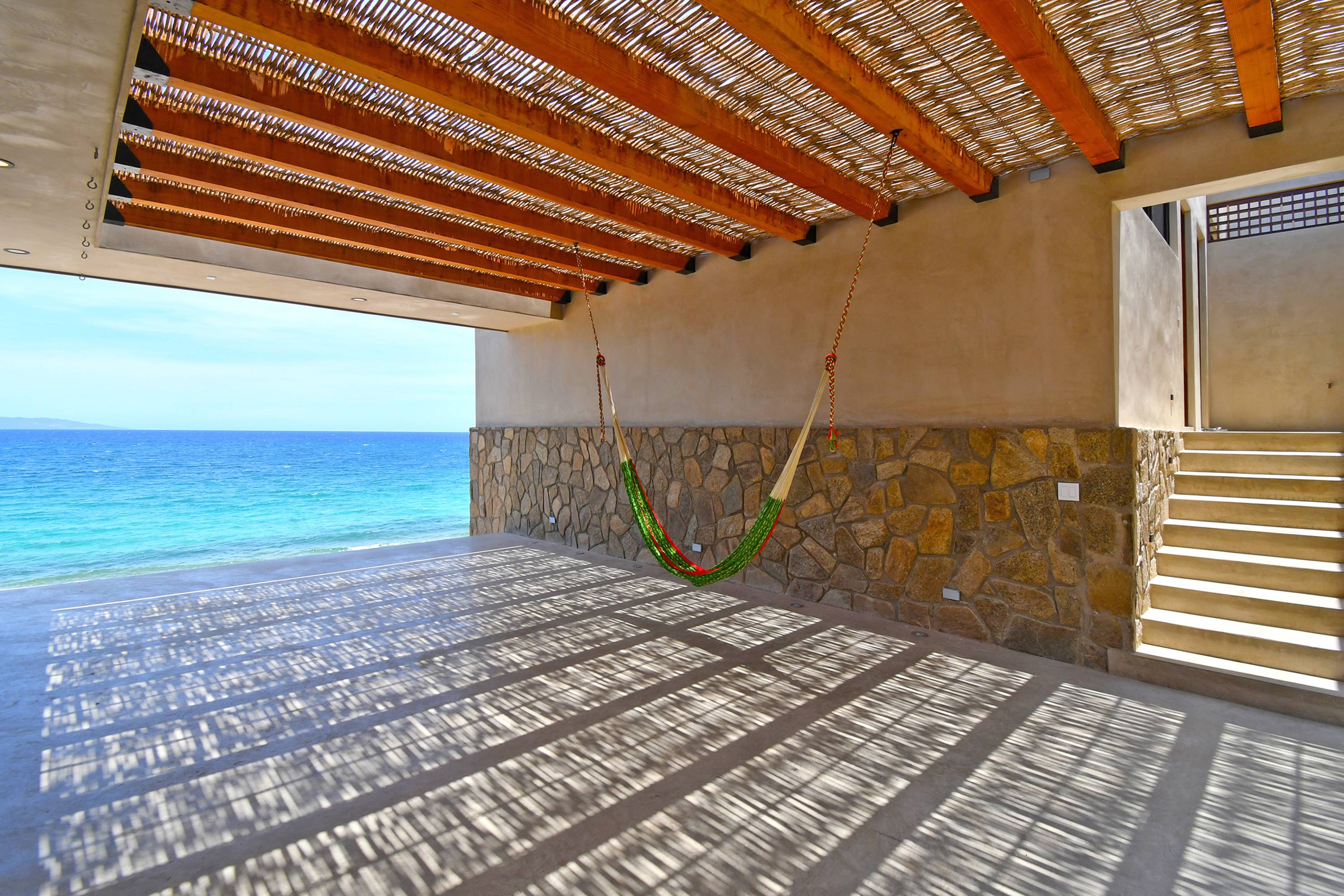 The patio between the two volumes, shaded by a wood-beam pergola, hammock strung across it.