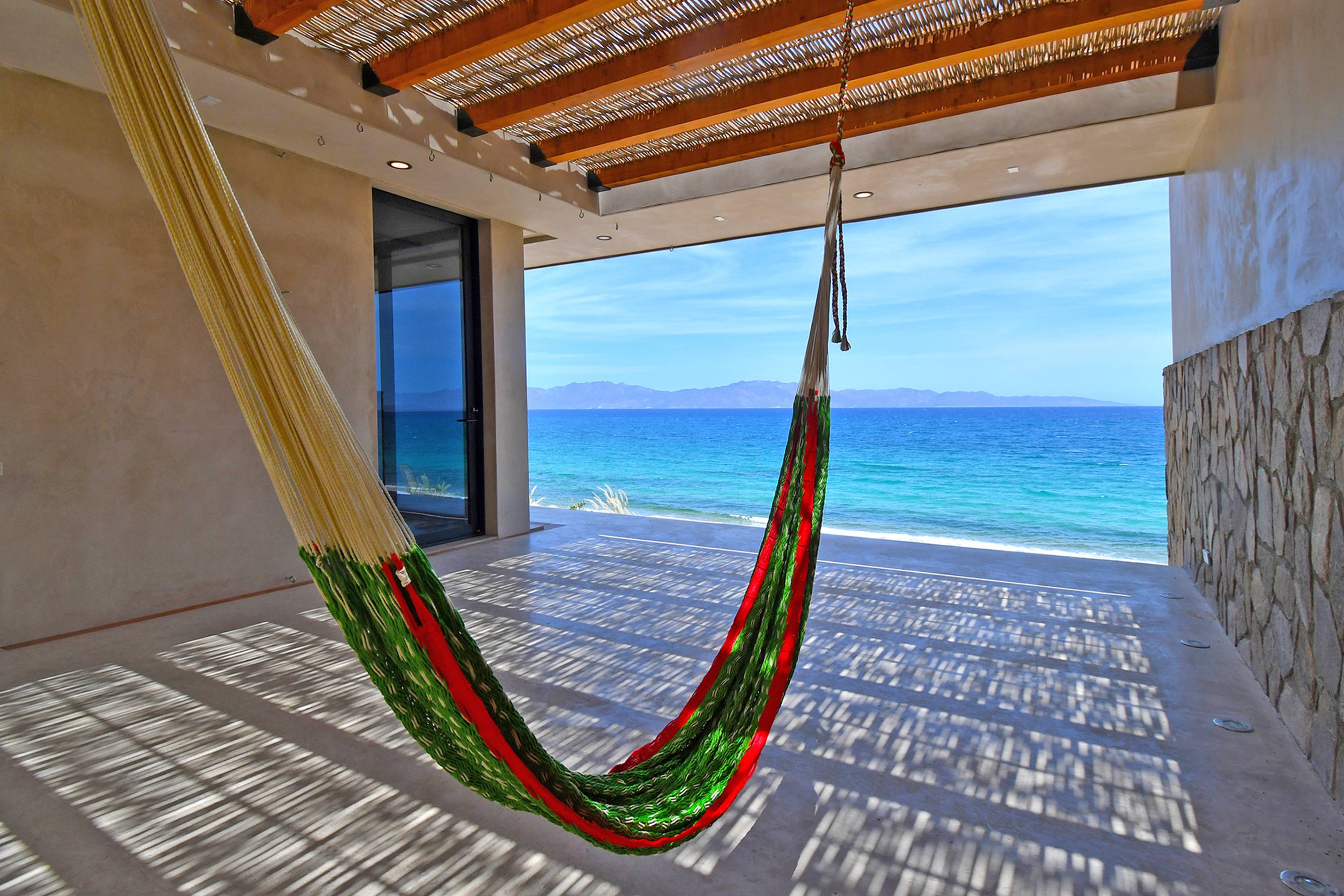 A hammock hanging on the shaded patio, the bay beyond.