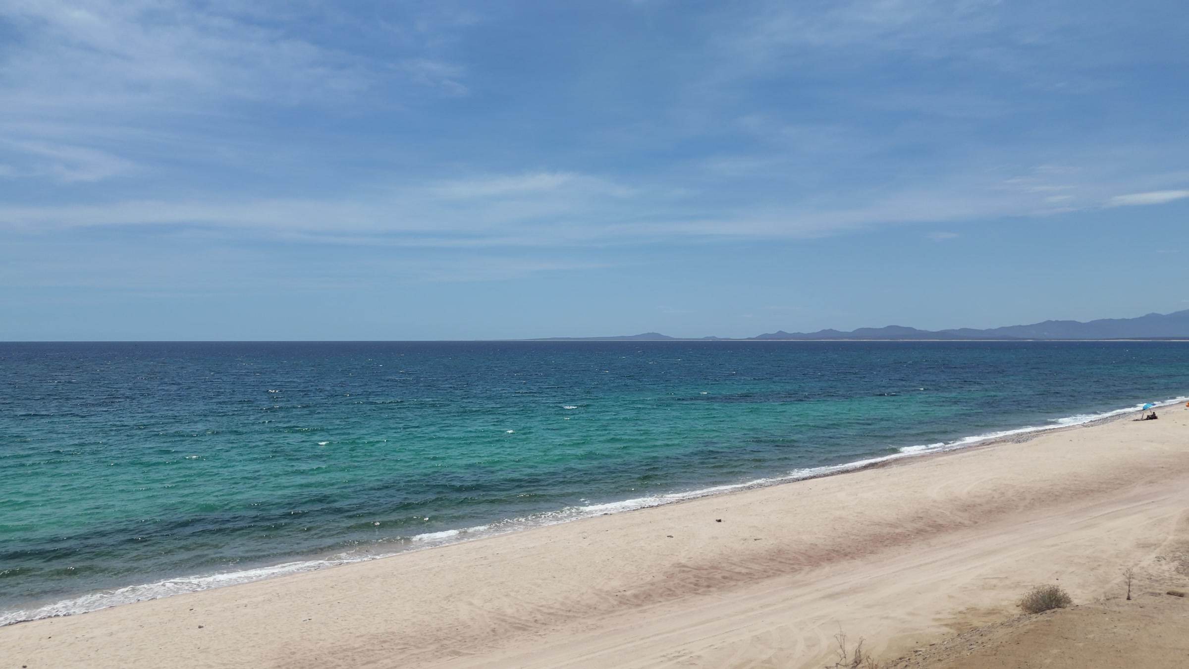 The bay flat and empty, looking down the beach toward the mountains.